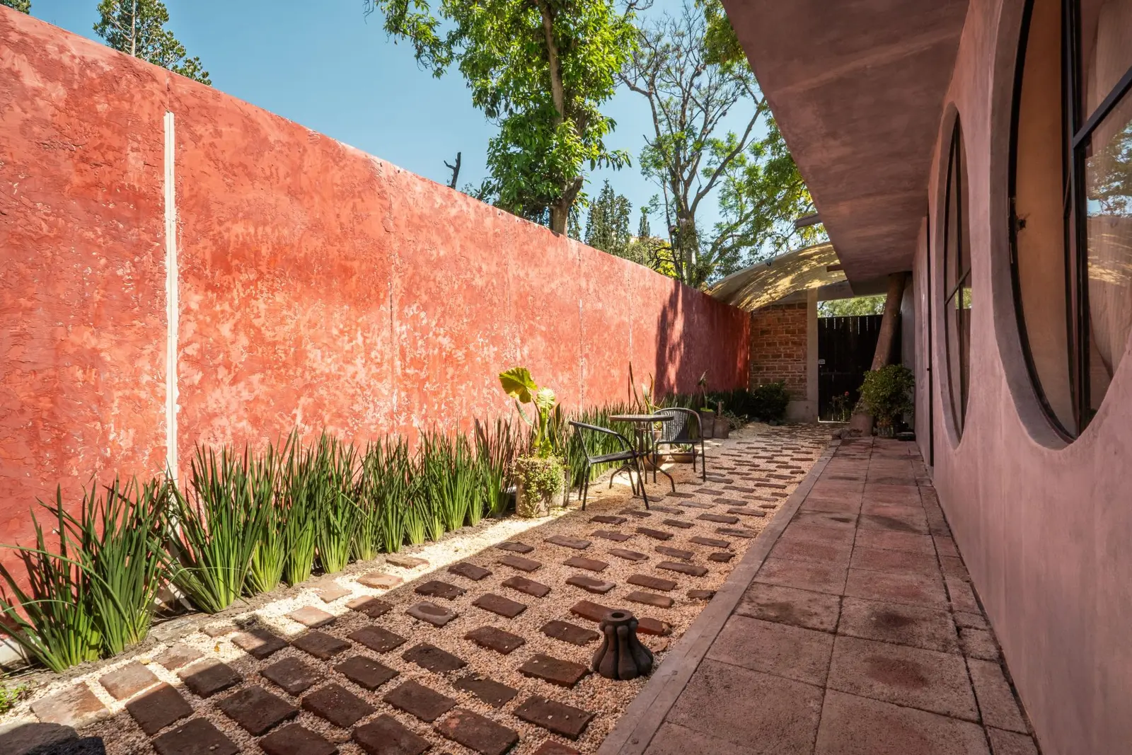 Patio de muros rojos con mesa y grava